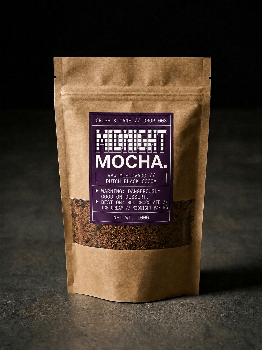 A 100g stand-up kraft paper pouch of Midnight Mocha coffee beans, featuring a dark purple label with white text, set against a dark, moody background.